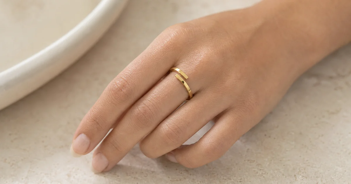 Un anillo abierto fino de acero inoxidable con dos extremos rectangulares pulidos y desplazados, puesto en un dedo