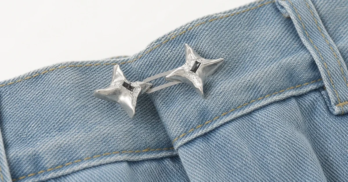 Clip plateado con dos estrellas unidas sobre la cintura de unos vaqueros azules